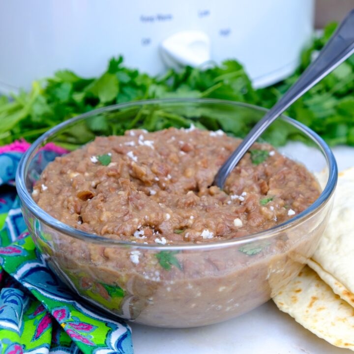 Homemade refried beans in a clear glass bowl.
