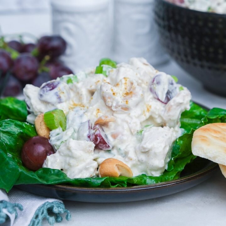 Curried chicken salad recipe with cashews and grapes on a bed of lettuce.