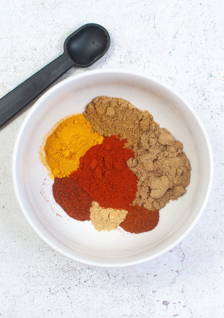 Spices in a white bowl to make a curry seasoning mix. 