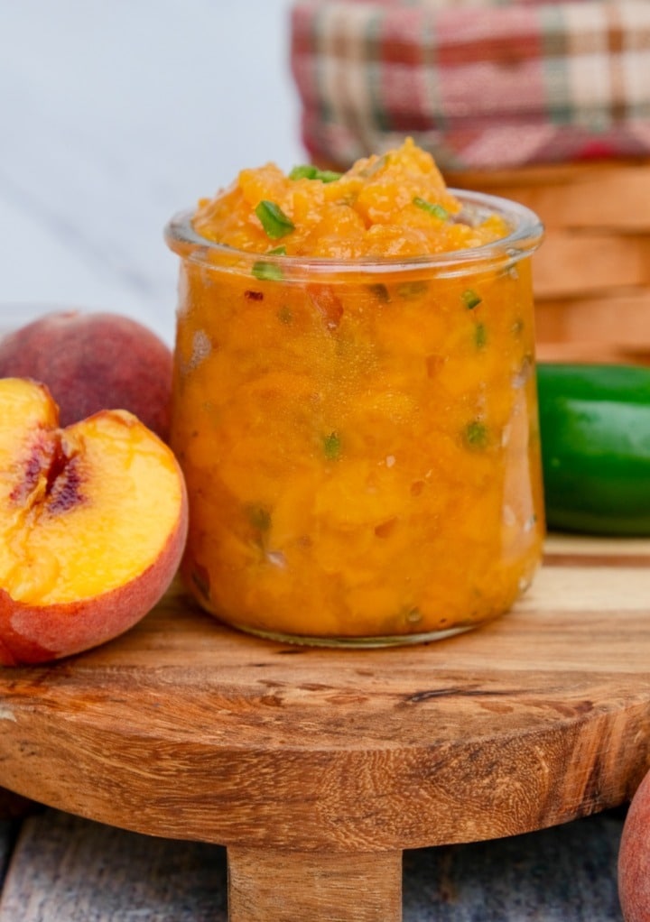 Homemade jam with fresh peaches in a serving glass jar. 