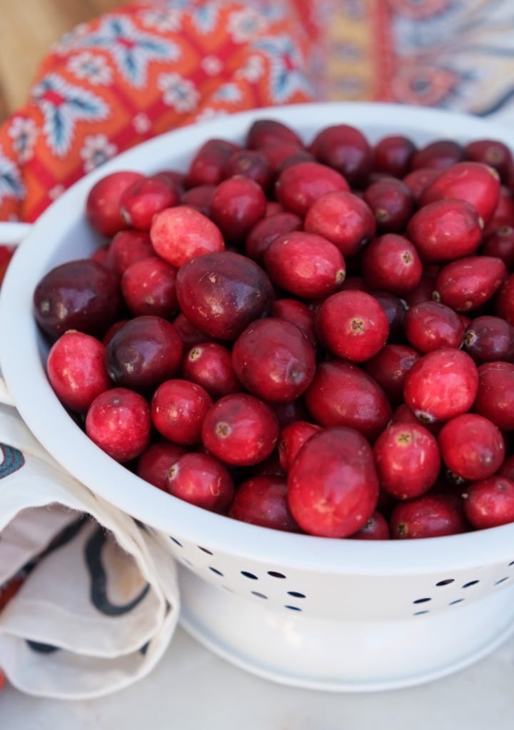 Fresh cranberries in a white colander.