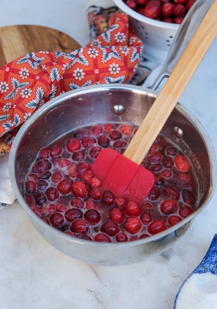 Cranberry sauce half way cooked in a small saucepan. 