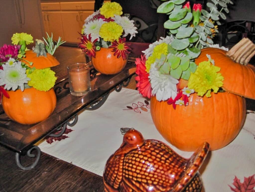 Table decorated with small pumpkins filled with fresh flowers.