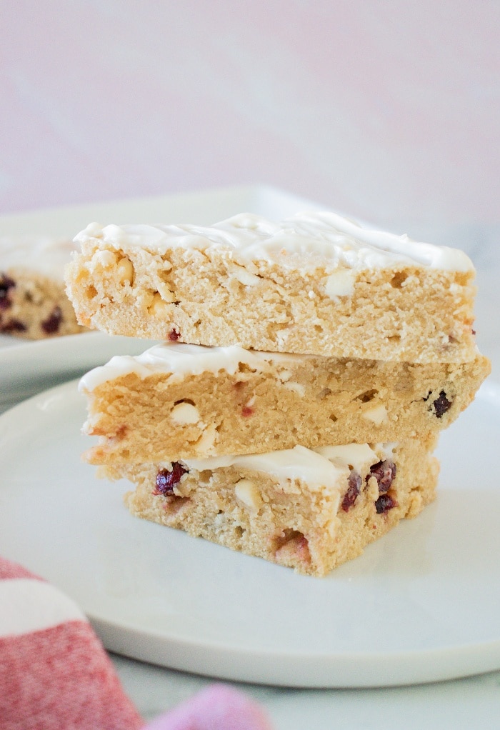 Three slices of cranberry bliss bar on a white plate ready to eat. 