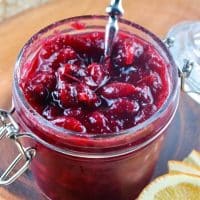 Ruby Red Cranberry Sauce in a mason jar with slices of oranges along the side showing the flavor addition #Cranberries #Thanksgiving #recipe | www.thefoodieaffair.com