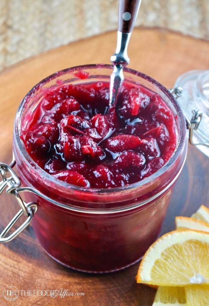 Ruby Red Cranberry Sauce in a mason jar with slices of oranges along the side showing the flavor addition #Cranberries #Thanksgiving #recipe | www.thefoodieaffair.com