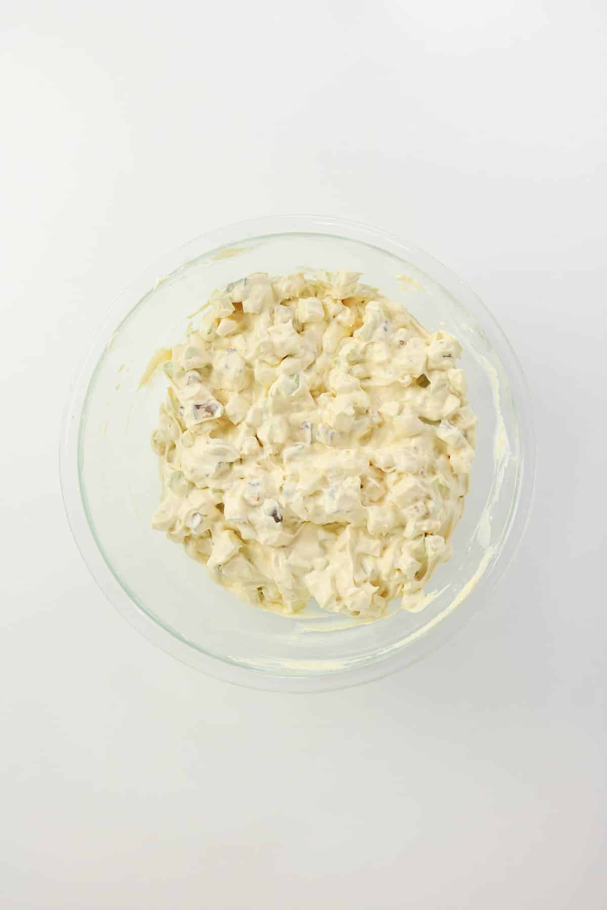 Apple Snickers salad in a clear mixing bowl before garnishing.