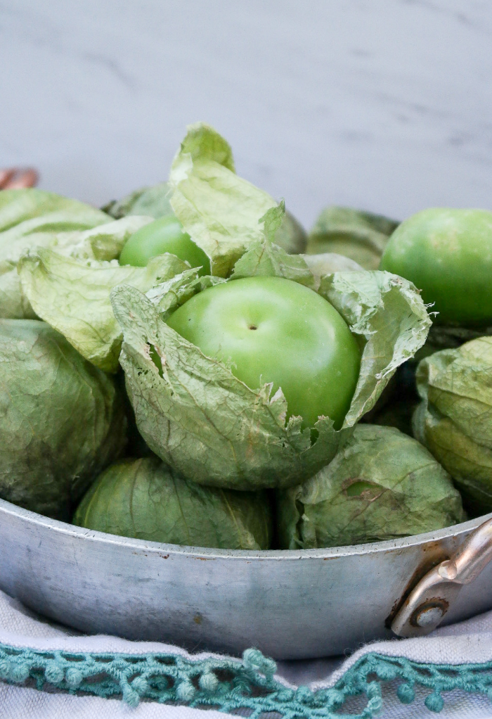 Fresh tomatillos in a stainless steel bowl.