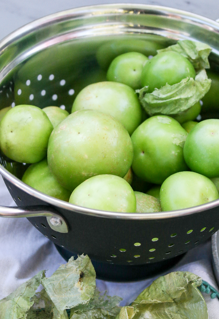 Fresh tomatillos in a colander to be washed.  