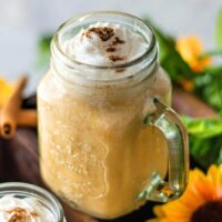 Pumpkin smoothie in a mason jar topped with whipped cream.