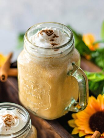 Pumpkin smoothie in a mason jar topped with whipped cream.