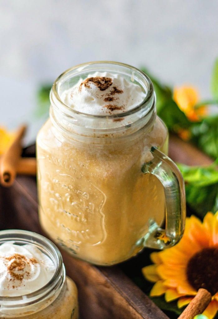 Pumpkin smoothie in a mason jar topped with whipped cream. 