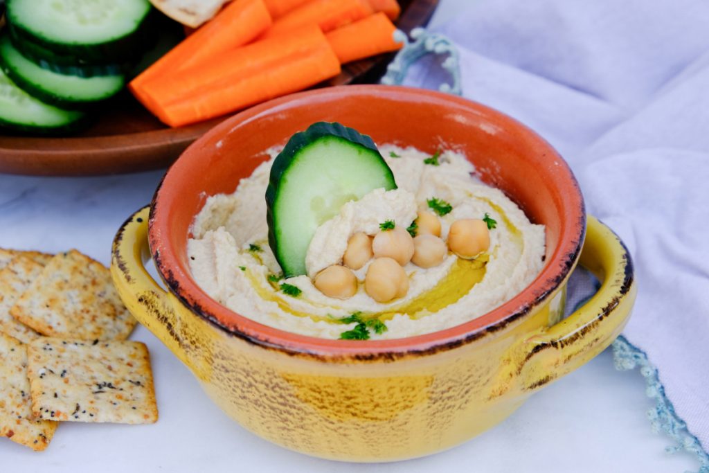 Homemade chickpea dip with a cucumber slice.