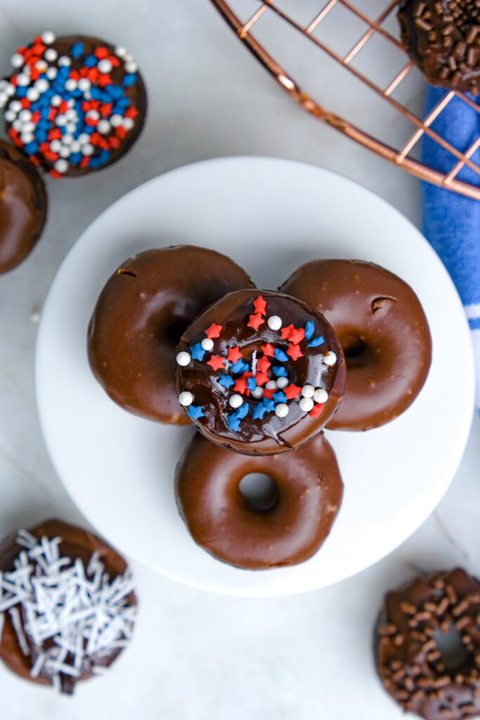 Overhead view of mini donuts on a white mini serving plate. 