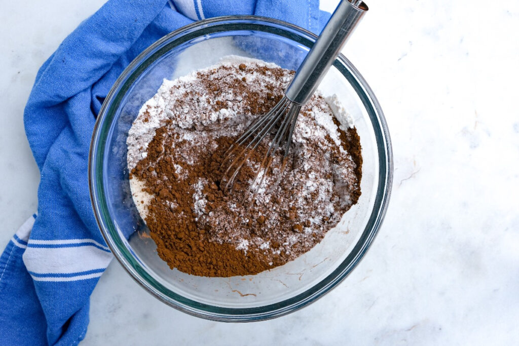 Dry ingredients in a clear mixing bowl to make mini chocolate donuts. 