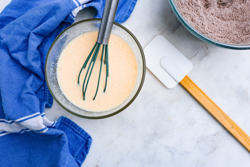 Wet ingredients in a small mixing bowl with a whisk in the center of the mix.