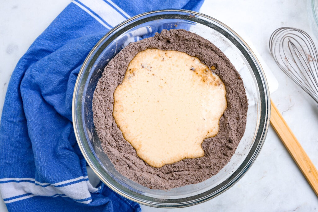 Chocolate donut dry ingredients with the egg mixture in the center of the mix before combining the ingredients. 