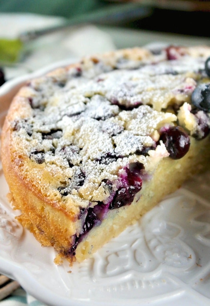 Blueberry coffee cake without streusel topping on a white cake plate 