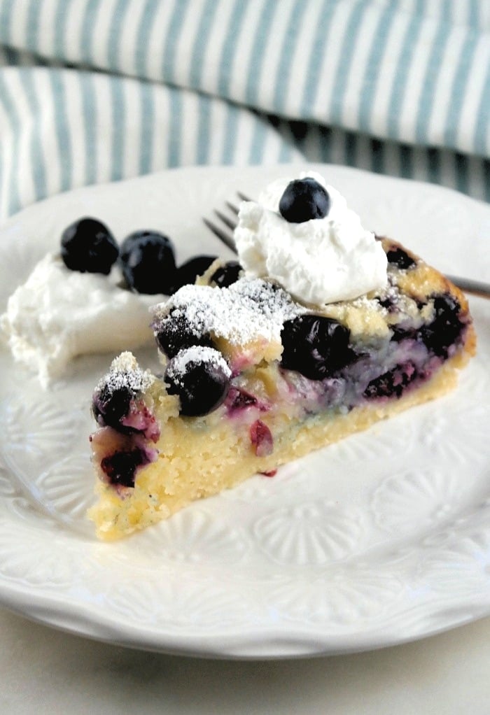 Slice of homemade blueberry coffee cake with whipped cream