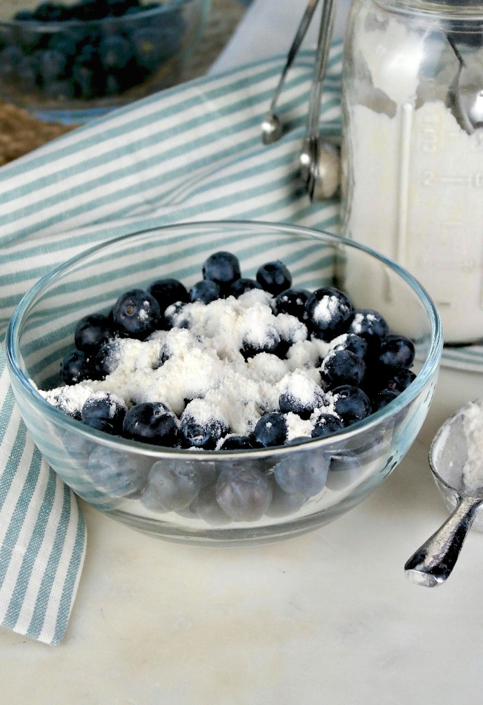 Flour added to blueberries for baking in a cake