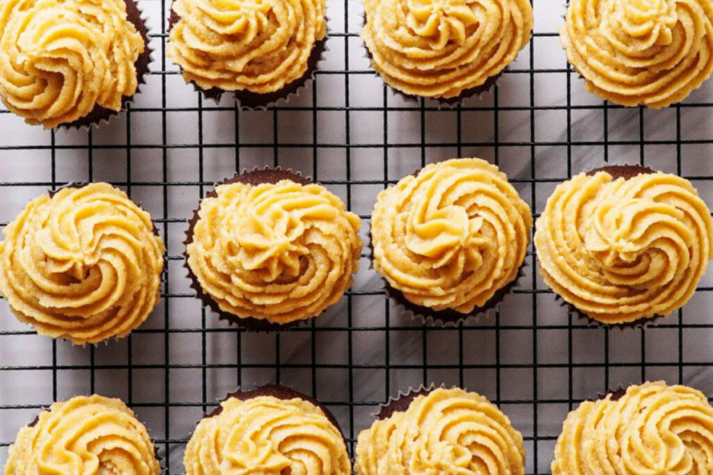 Top view of cupcakes topped with peanut butter frosting on a baking rack. 