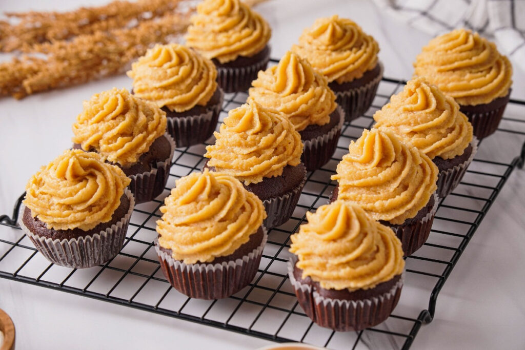 Chocolate cupcakes topped with peanut butter frosting on a baking cooling rack. 