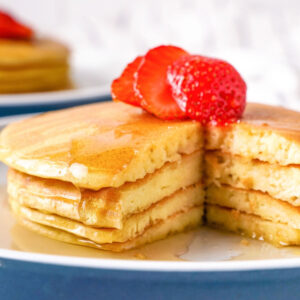 Cottage cheese pancakes on a white plate with a blue rim ready to eat.