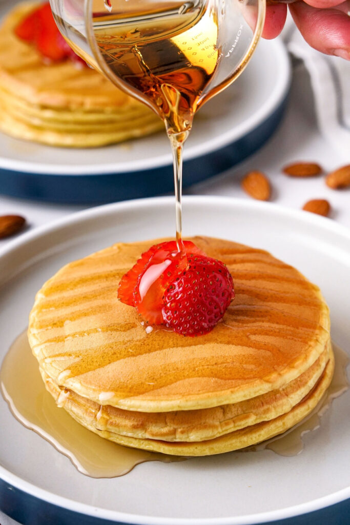 Pancakes made with cottage cheese topped with maple syrup with sliced strawberry. 