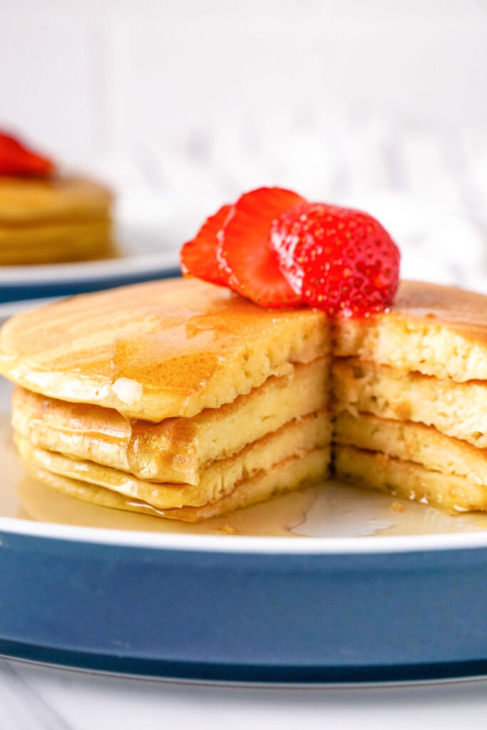 Cottage cheese pancakes with a wedge cut out on a white place with a blue rim.