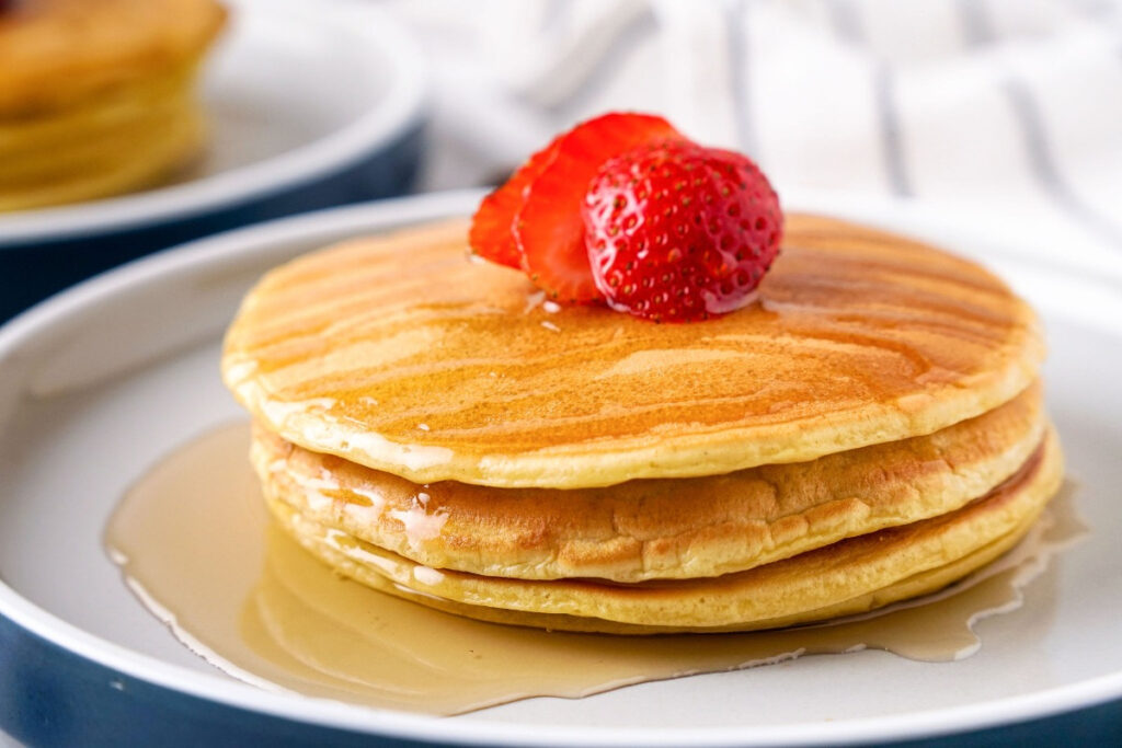 A stack of pancakes on a white serving plate. 