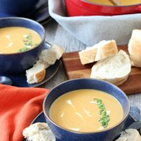 Finished sweet potato soup with coconut milk in a bowl with some bread on the side.