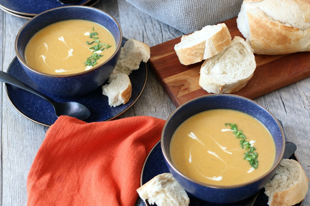 Close up of the finished sweet potato soup in bowls with bread on the side ready to be enjoyed.