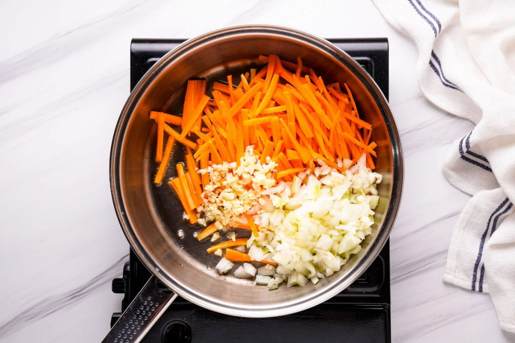 Vegetables sautéing in a large skillet. 