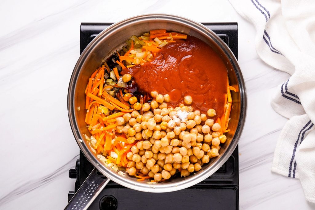 Chickpeas added to a skillet with sautéed vegetables. 