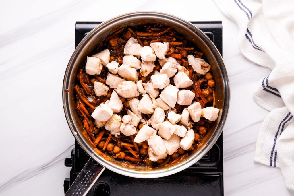 Chickpea stew in a skillet topped with cooked diced chicken.