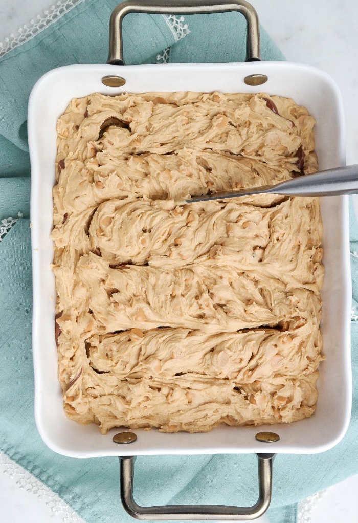 Cookie dough in a baking pan with a knife swirling the batter. 