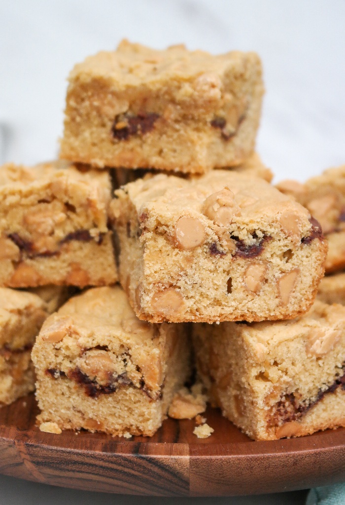 A stack of cookie bars on a wooden plate. 