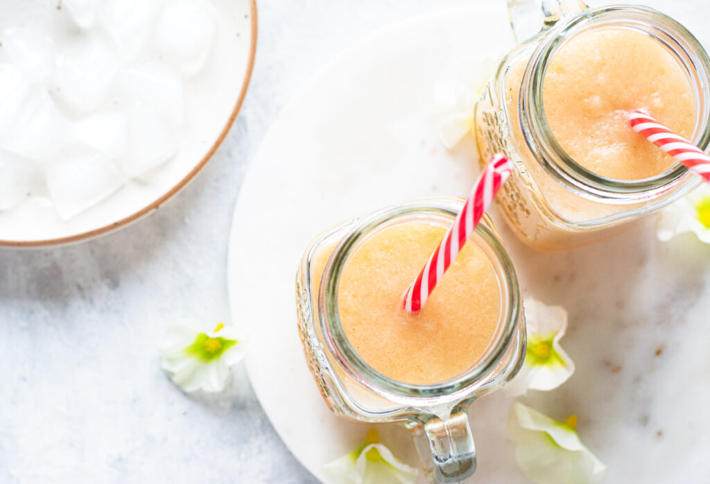 Overhead shot of two mason jar glasses of pineapple melon smoothies