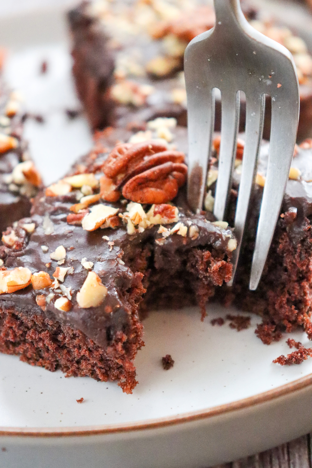 A slice of Texas sheet cake topped with pecans. . 