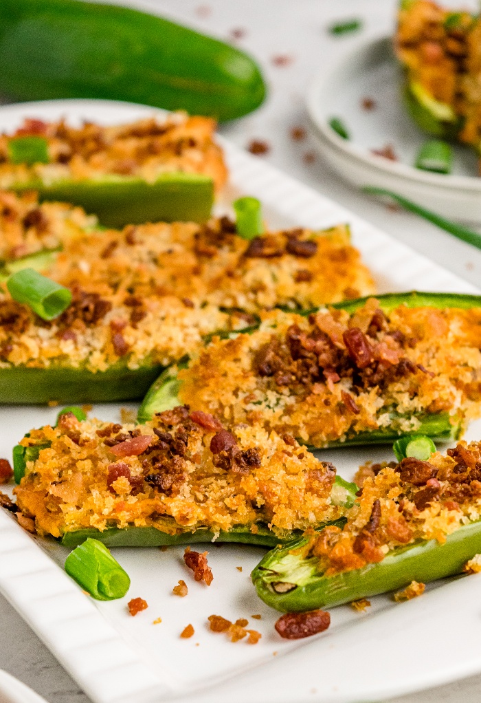 Jalapenos sliced and filled with cheese on a white serving plate. 