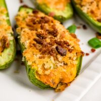 A cheese stuffed jalapeno on a white serving dish.