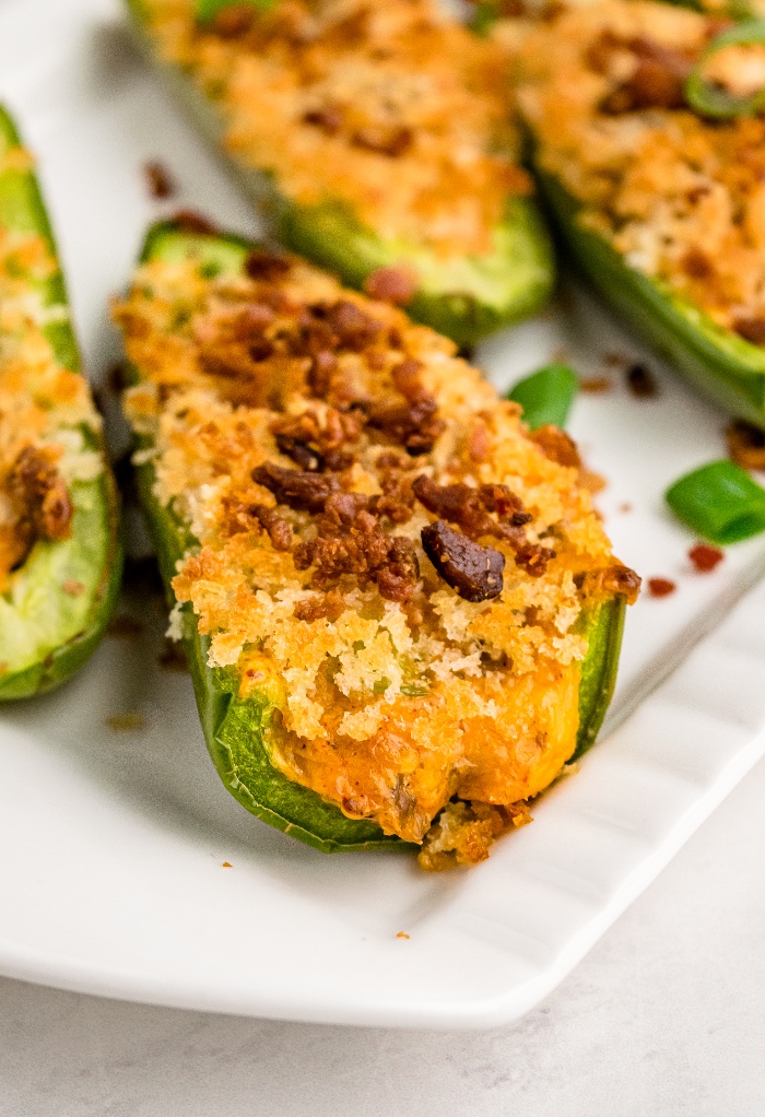 A cheese stuffed jalapeno on a white serving dish.