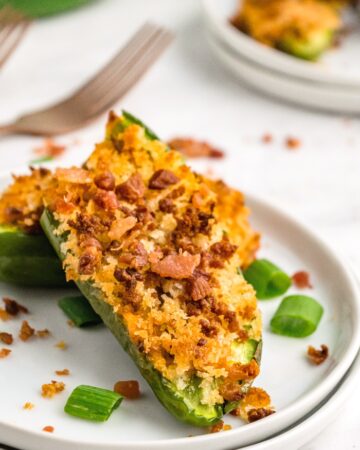Jalapeno stuffed with sausage on a white serving plate.
