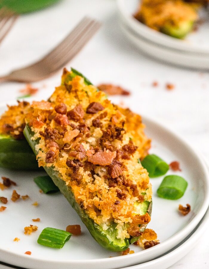 Jalapeno stuffed with sausage on a white serving plate.