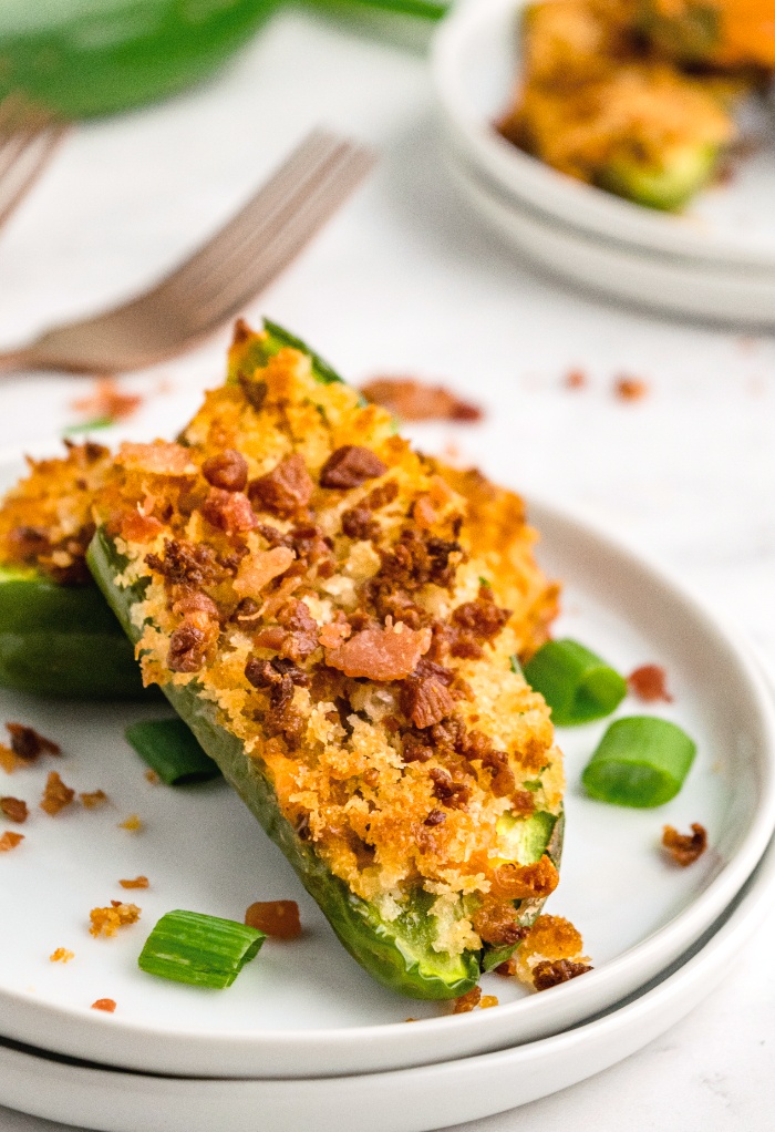Jalapeno stuffed with sausage on a white serving plate.