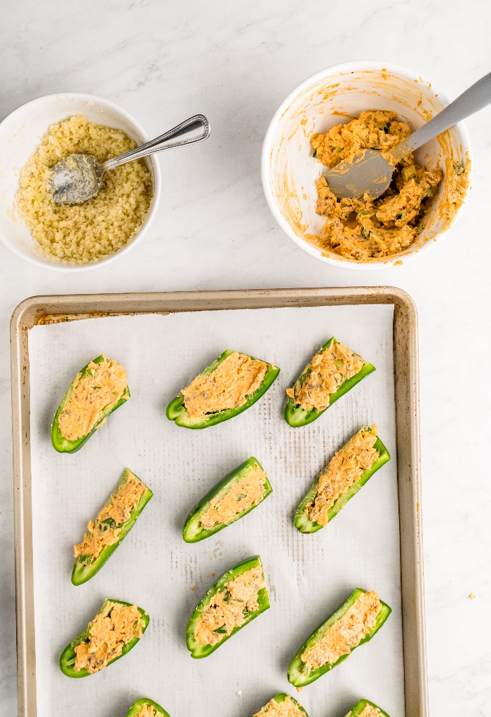 Stuffed jalapenos on a baking sheet.