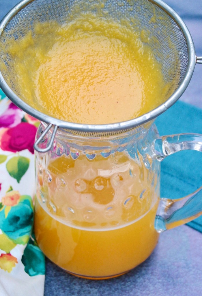 peach pulp straining into a glass pitcher
