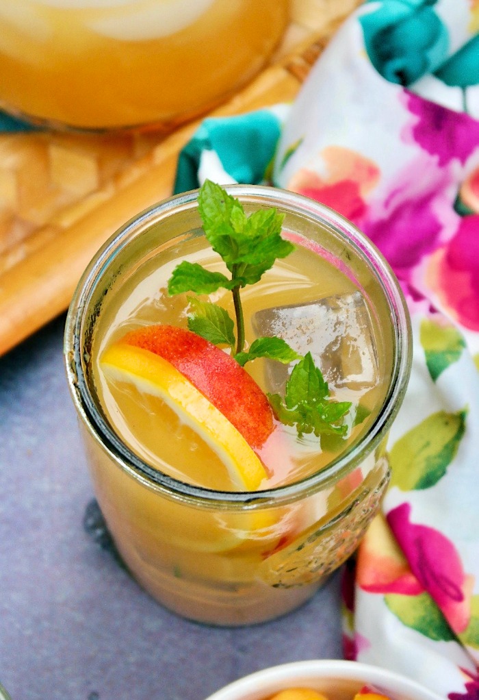 Top view of peach lemonade with a slice of peach and lemon with mint.