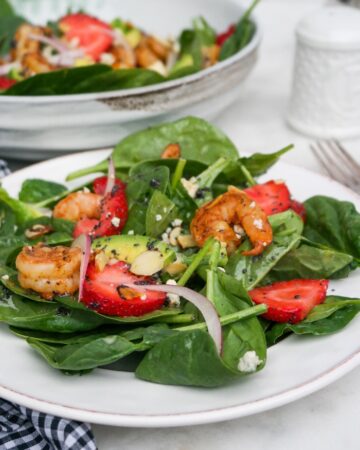 Spinach Strawberry salad on a white plate ready to eat.