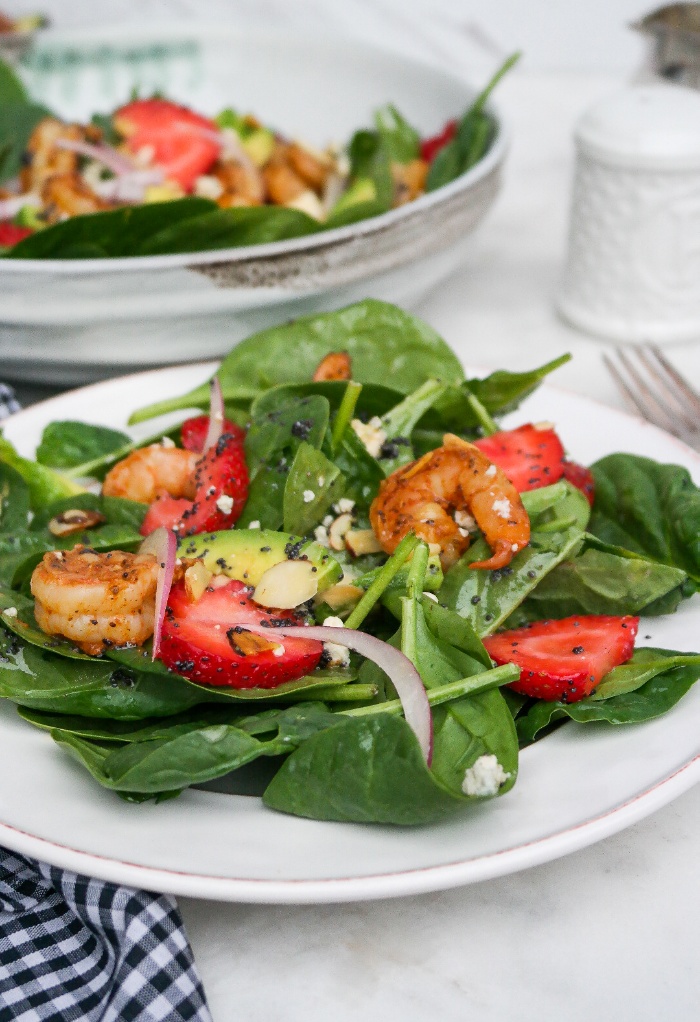 Spinach Strawberry salad on a white plate ready to eat.